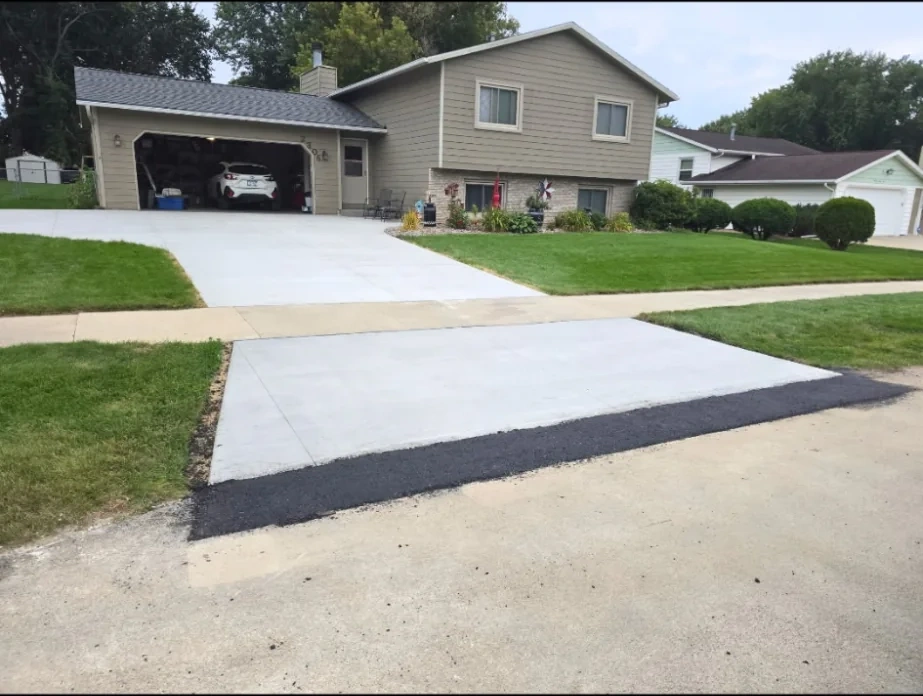 Concrete driveway meeting black asphalt apron at the street in southern Minnesota